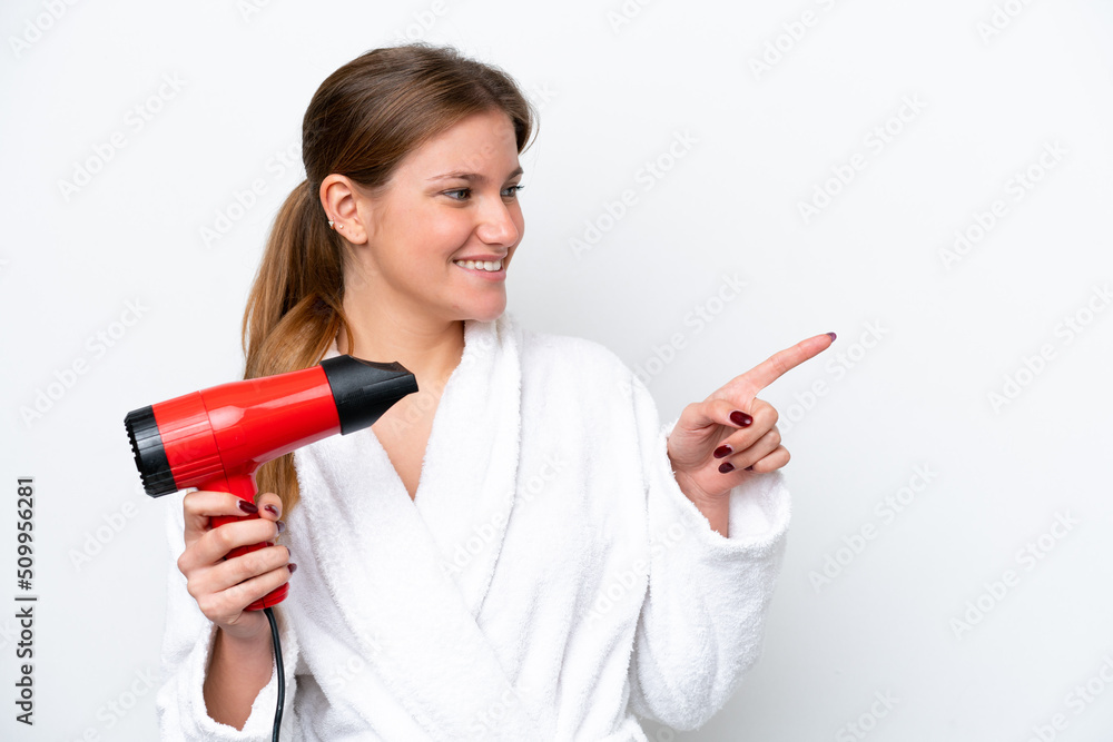 Young caucasian woman holding hairdryer isolated on white background pointing to the side to present a product Young caucasian woman holding hairdryer isolated on white background pointing to the side to present a product