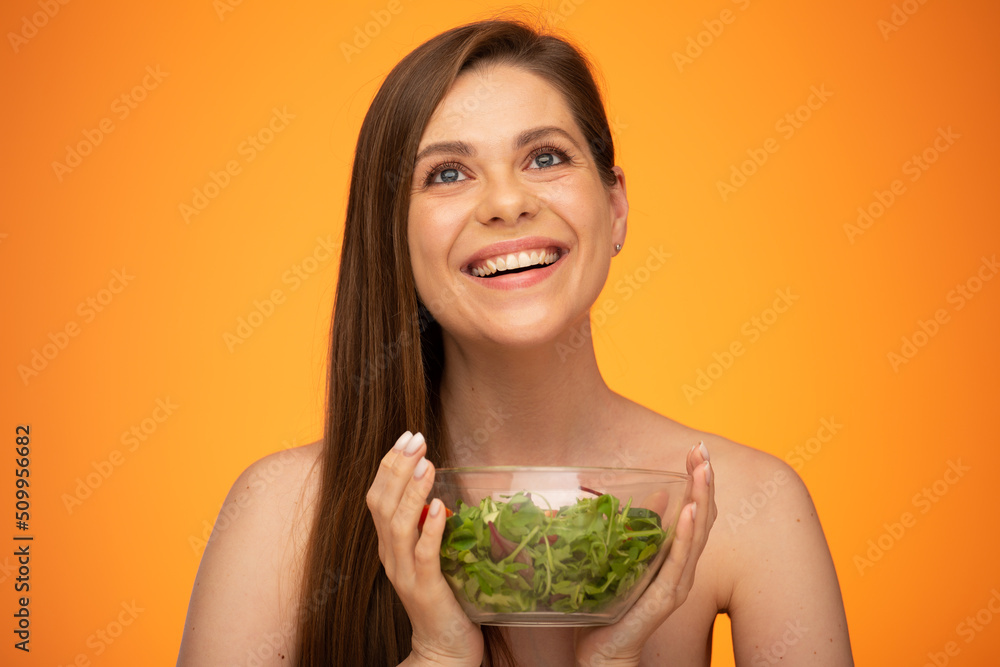 Happy laughing woman with bare shoulders holding green salad isolated portrait. Girl with long hair. Happy laughing woman with bare shoulders holding green salad isolated portrait. Girl with long hair.