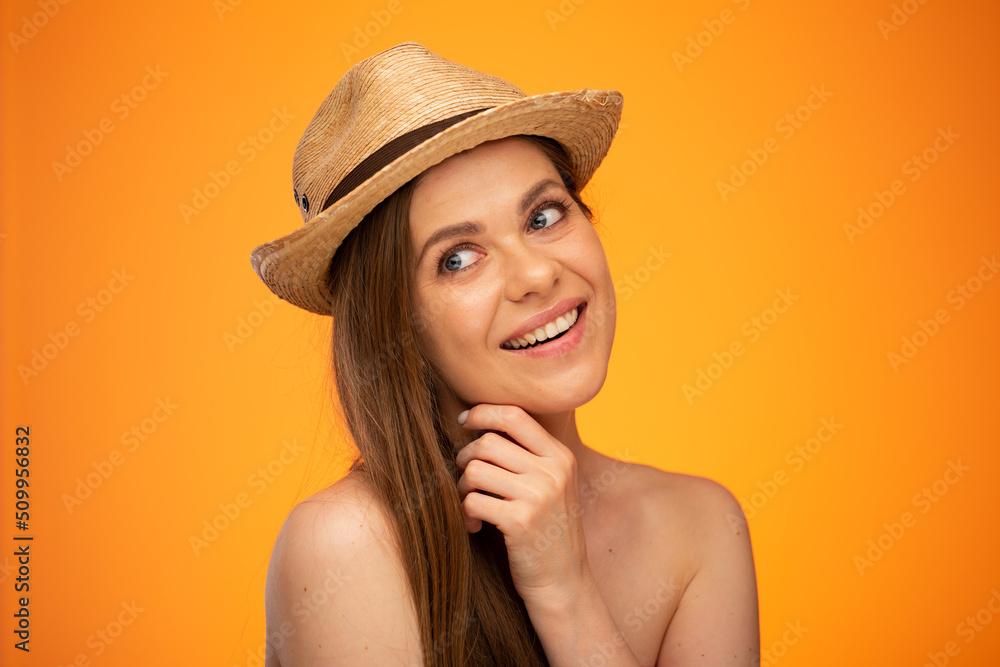 Young woman with bared shoulders looking away face isolated portrait on orange background. Girl wearinh summer hat. Young woman with bared shoulders looking away face isolated portrait on orange background. Girl wearinh summer hat.