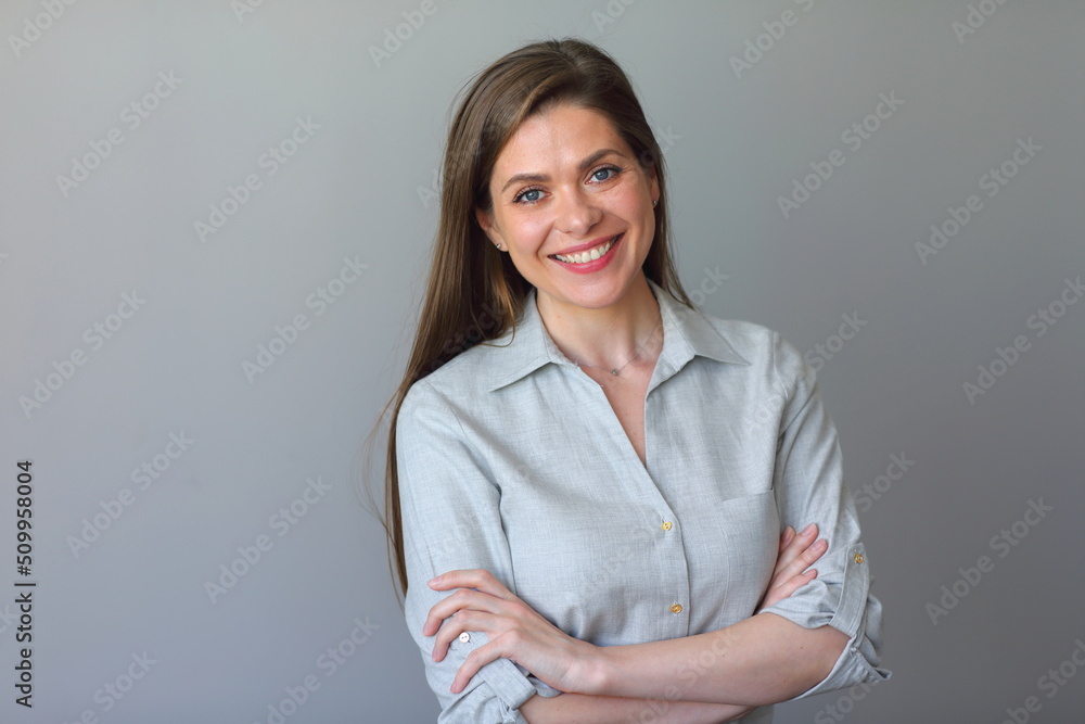 Smiling woman in grey shirt standing with crossed arms. Smiling woman in grey shirt standing with crossed arms.