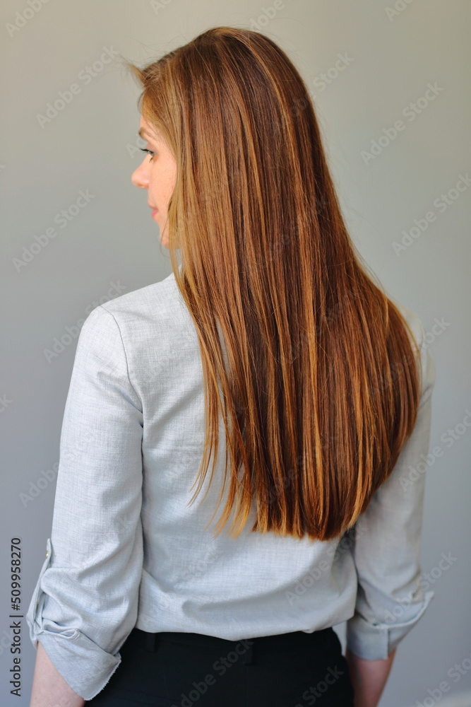 Woman with long brown hair standing back.
