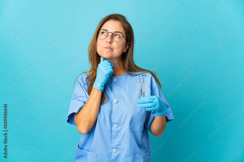 Middle age dentist Brazilian woman holding tools over isolated background having doubts Middle age dentist Brazilian woman holding tools over isolated background having doubts