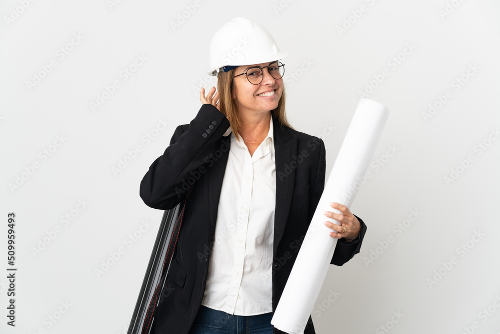 Middle age architect woman with helmet and holding blueprints over isolated background having doubts Middle age architect woman with helmet and holding blueprints over isolated background having doubts