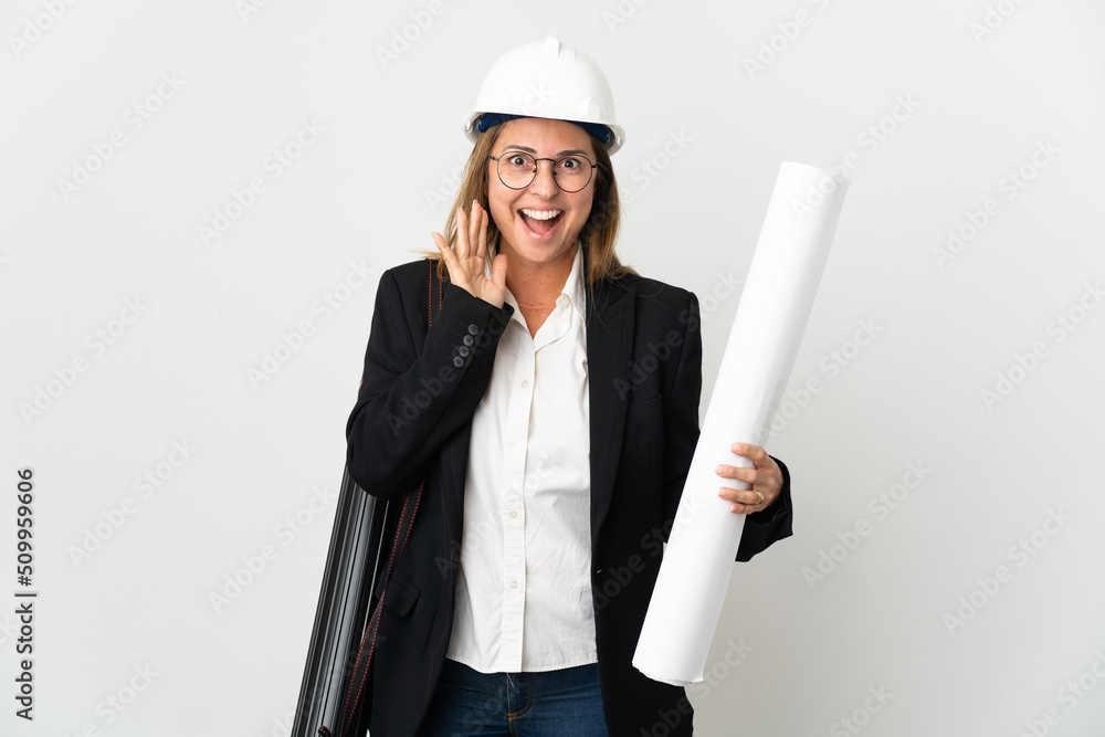 Middle age architect woman with helmet and holding blueprints over isolated background shouting with mouth wide open Middle age architect woman with helmet and holding blueprints over isolated background shouting with mouth wide open