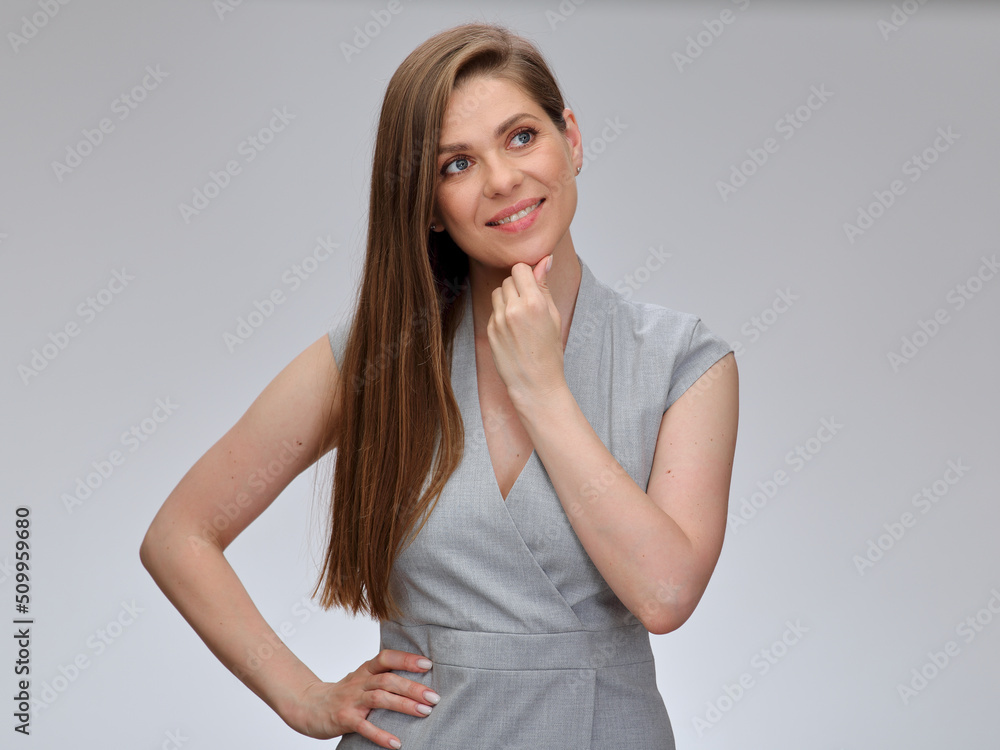 Obraz premium Thinking and smiling business woman touching her chin and holding one hand on hip looking up. isolated female portrait.