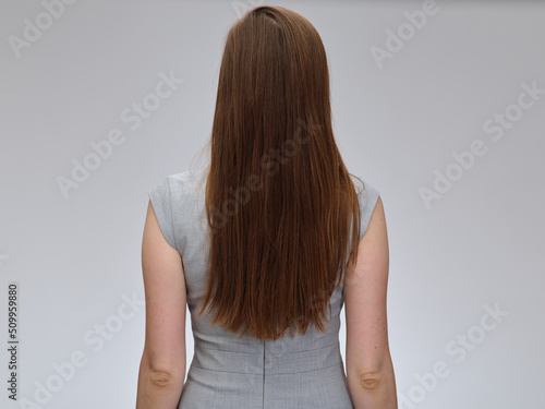 Woman back standing with long hair wearing business dress, isolated portrait.