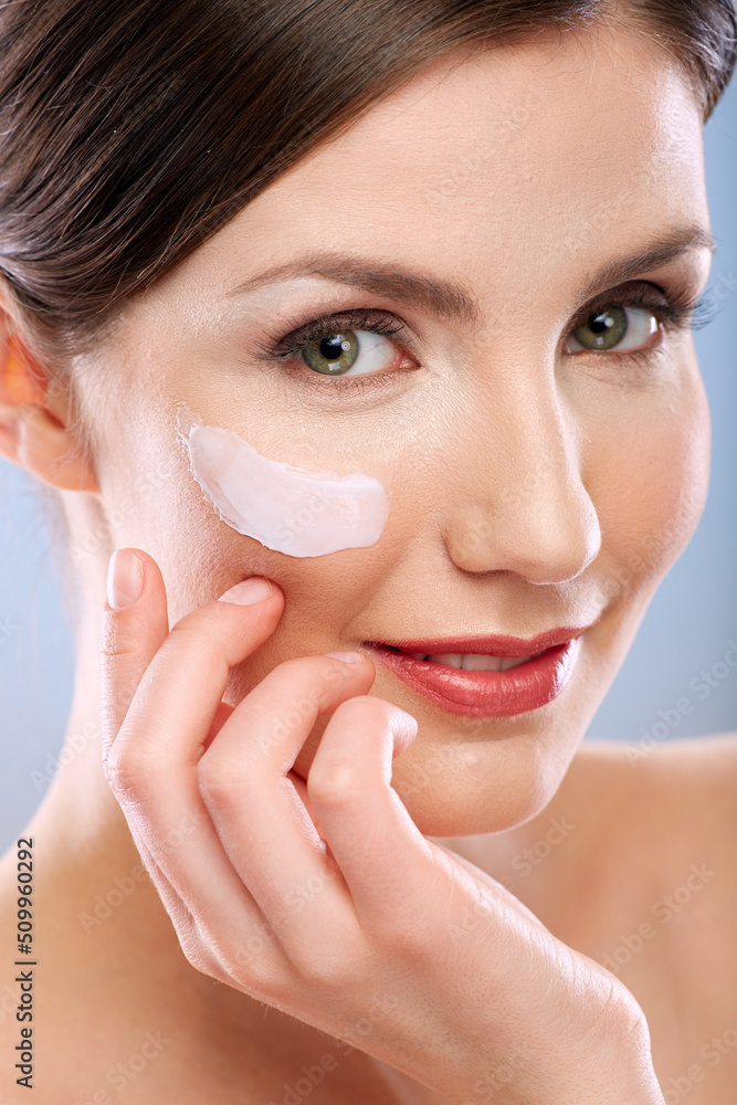 Beauty portrait of smiling woman with moisturizer on face.