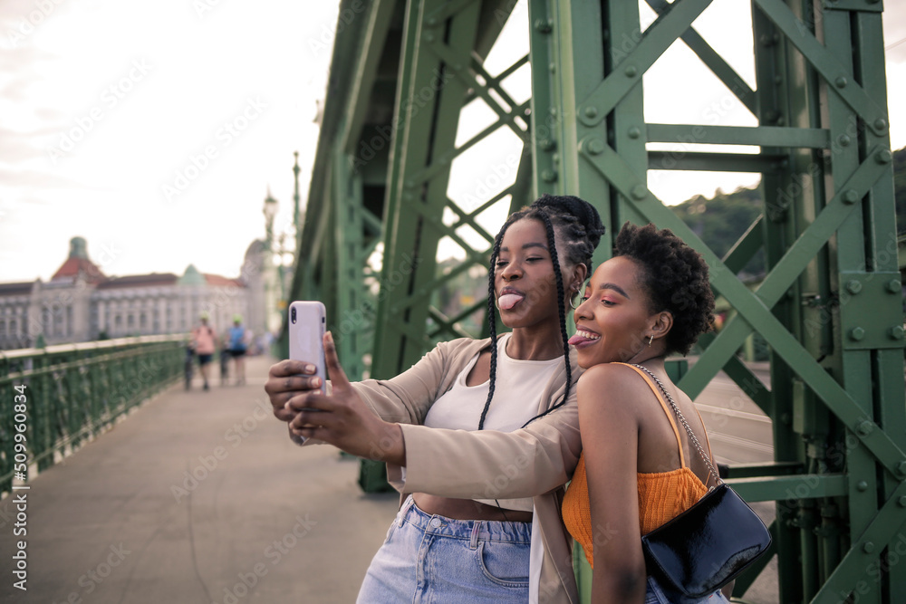 African girls are taking selfie together, outside, visiting the city