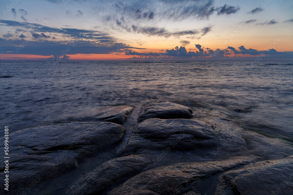 Boulders and rocks in the surf on coast of the Baltic sea at sunset, long exposure