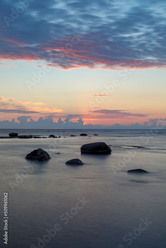 Boulders and rocks in the surf on coast of the Baltic sea at sunset  long exposure