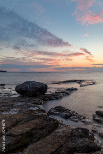 Boulders and rocks in the surf on coast of the Baltic sea at sunset, long exposure