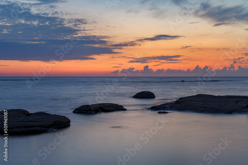 Boulders and rocks in the surf on coast of the Baltic sea at sunset, long exposure
