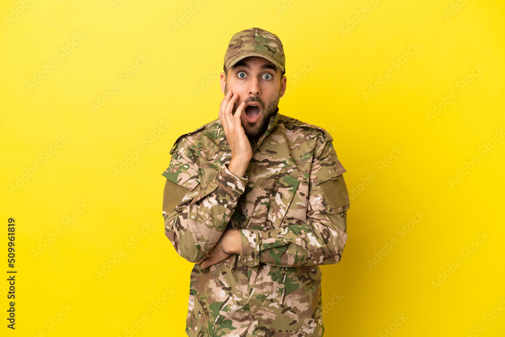 Military man isolated on yellow background surprised and shocked while looking right Military man isolated on yellow background surprised and shocked while looking right