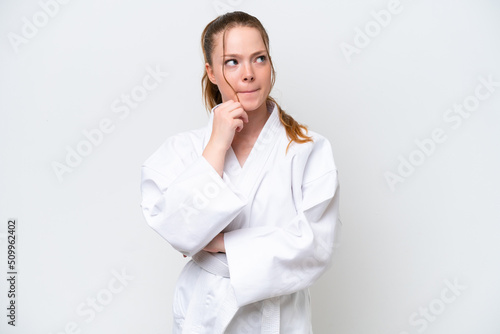 Young caucasian girl doing karate isolated on white background having doubts and thinking
