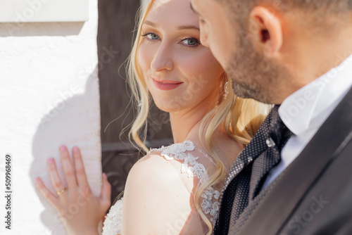 Tableau sur toile Portrait of young blonde bride in white dress and brunet groom in suit smiling and walking on city street in Italy closeup, urban background