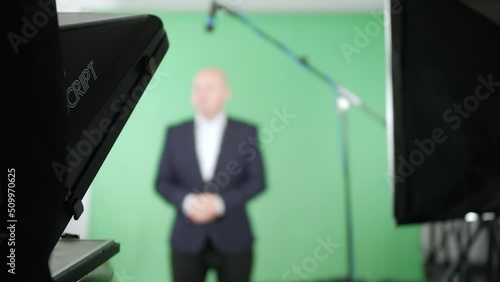 Television presenter talking to camera using a teleprompter in a green screen studio photo