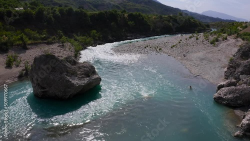 Aerial view of solo man bathing in fresh flowing waters of  of Vjose river enjoying picturesque sight of mountains. photo