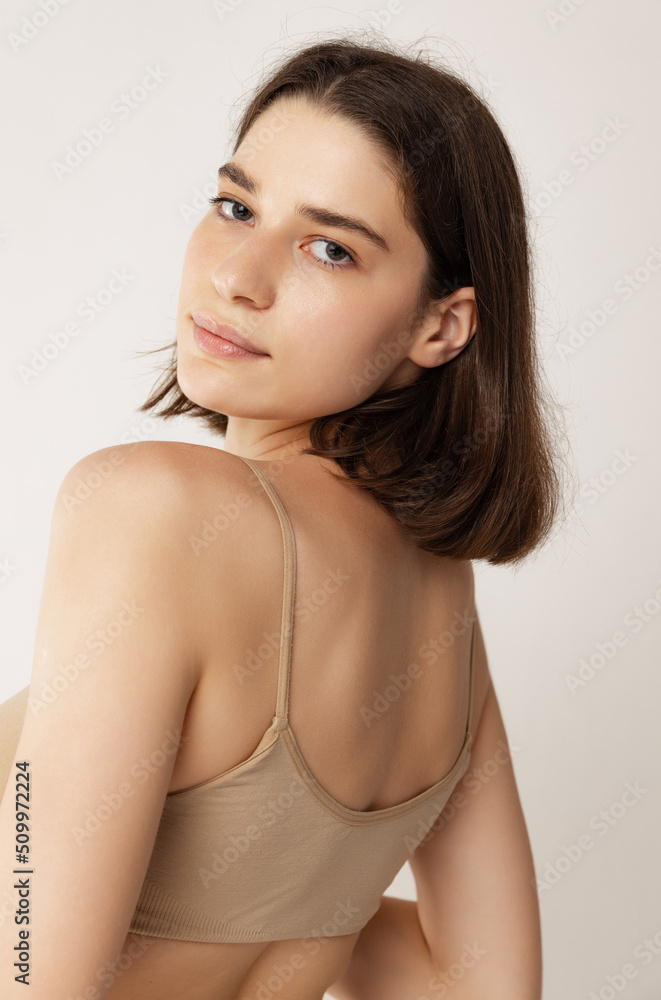 Close-up portrait of young beautiful woman with short brown hair posing isolated over grey studio background Close-up portrait of young beautiful woman with short brown hair posing isolated over grey studio background
