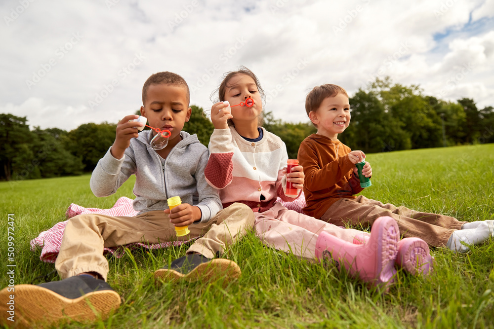 childhood, leisure and people concept - group of children blowing soap bubbles at park childhood, leisure and people concept - group of children blowing soap bubbles at park