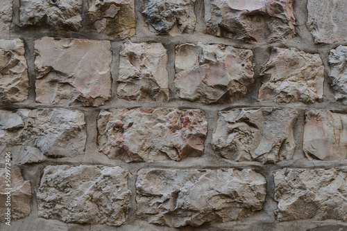 Wall of untreated natural stone. Horizontal rows stones. Textured surface stone. photo