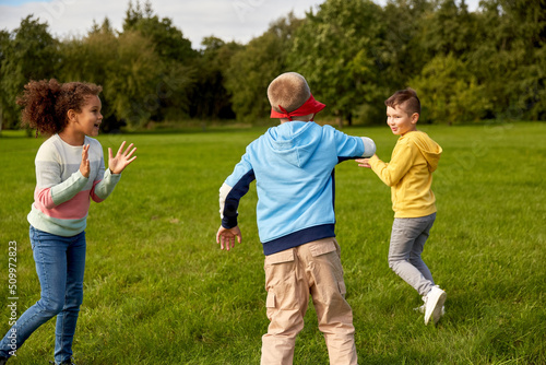 childhood, leisure and people concept - group of happy children playing tag game and running at park © Syda Productions