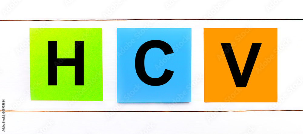 On a white wooden background there are three colorful bright stickers with text HCV On a white wooden background there are three colorful bright stickers with text HCV
