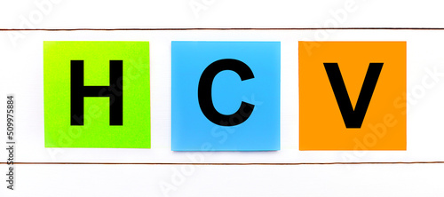 On a white wooden background there are three colorful bright stickers with text HCV photo