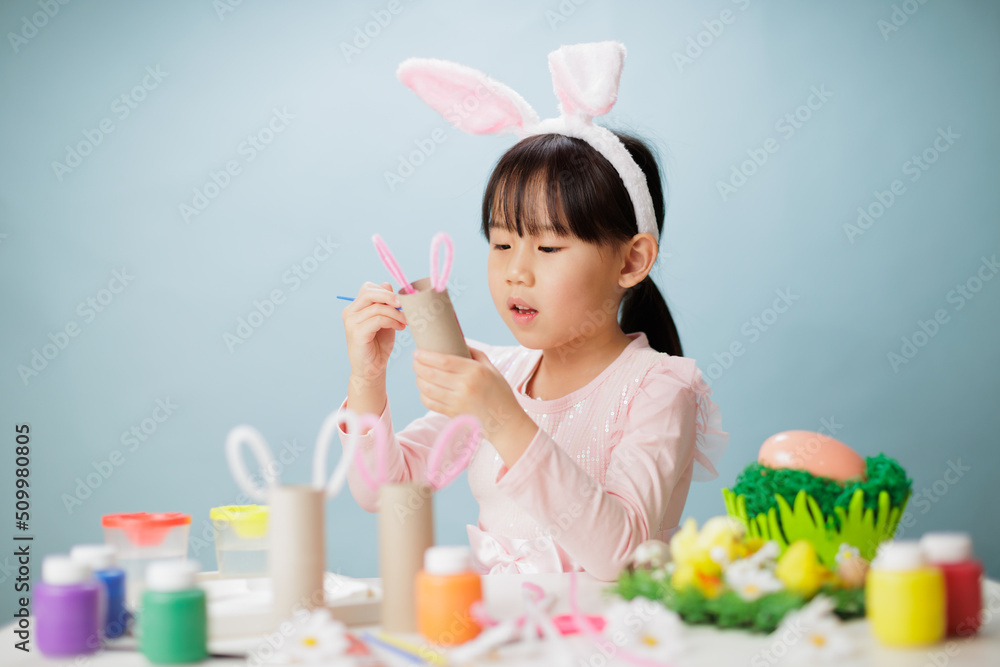 young girl making easter craft against plain background young girl making easter craft against plain background