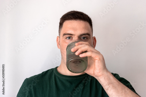 Photos Young man is drinking water in a crystal glass.
