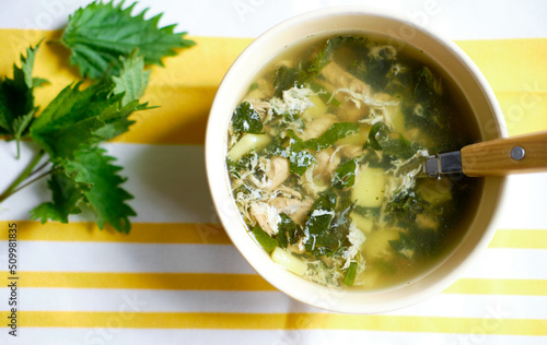 vitamin nettle soup. bright yellow background and green nettles on the table, top view. Healthy summer soup.