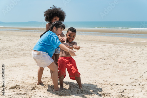 Happy kids play tug-of-war on the beach