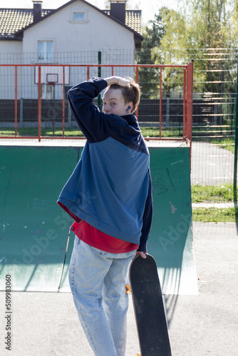 A modern teenager who is passionate about his hobby and extreme sports rides a skateboard, on a sports field, in the fresh air. Modern style. photo