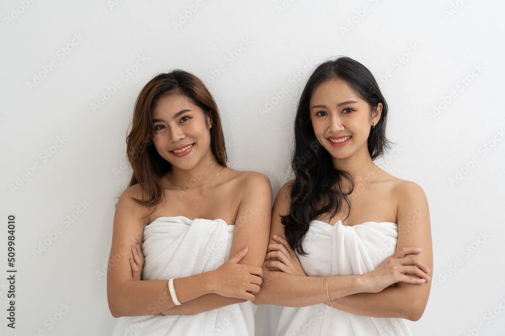 Portrait of Smiling young LGBT lesbian couple wearing a white towel standing and hugging each other affectionately together. Portrait of Smiling young LGBT lesbian couple wearing a white towel standing and hugging each other affectionately together.