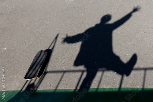 The falling active shadow in motion on the asphalt on the sports field. Entertainment of modern teenagers. Complex, transitional period in a teenager. Loneliness. photo