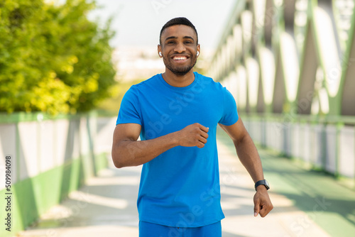 Portrait of an athletic young man running outdoors on a bridge
