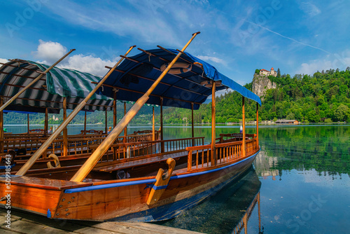 Traditional Pletna boat on the Bled lake. A boat that transports tourists to the island where the church Assumption of Maria .In the background is the famous old castle on the cliff. Bled, Slovenia