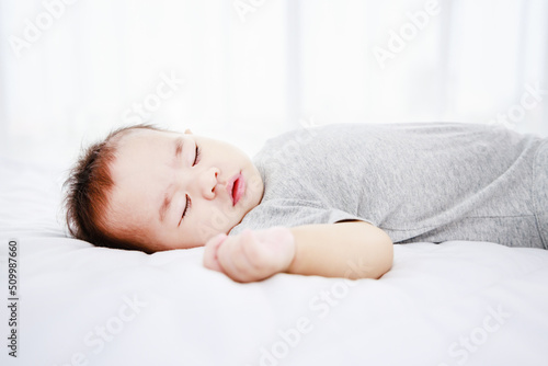 Sleeping cute baby girl on bed during the daytime. Protection of children.