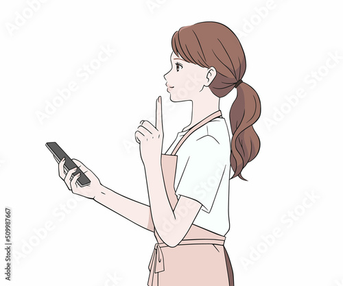 スマートフォンを持ち、人差し指を立てるエプロン姿の女性