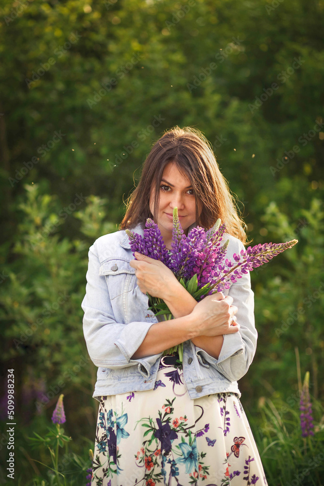 Sunny portrait of a charming girl hugging a bouquet of purple lupins. Sunny portrait of a charming girl hugging a bouquet of purple lupins.