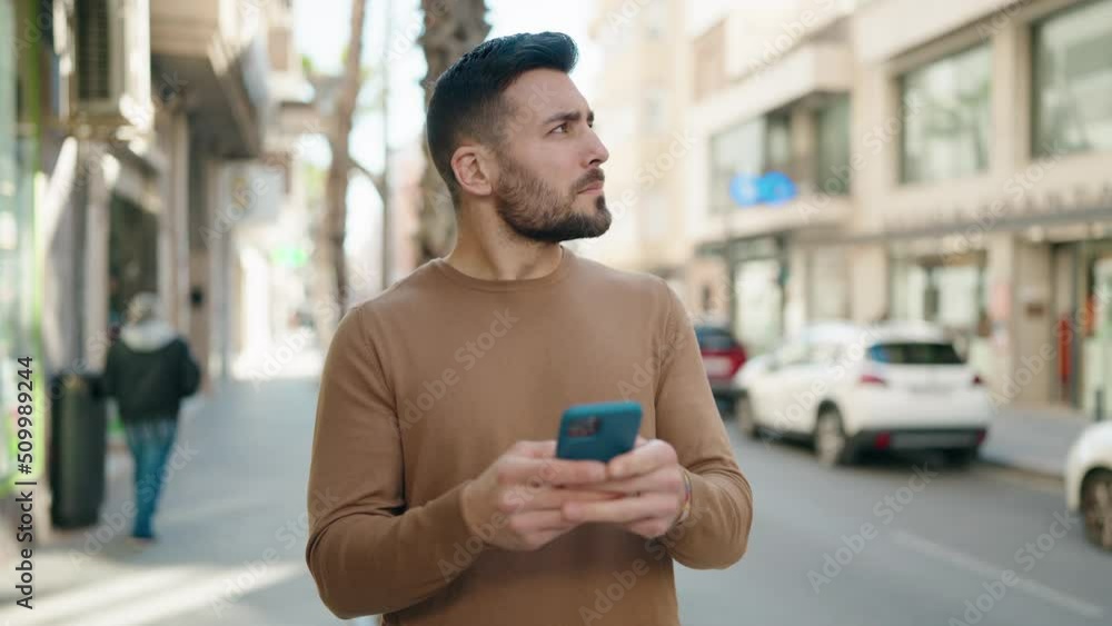 Young hispanic man using smartphone at street Young hispanic man using smartphone at street
