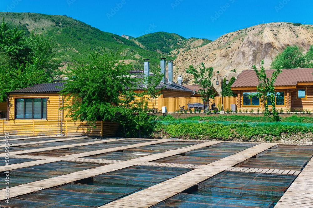 fish farm in a mountain valley with aquaculture cages and wooden buildings