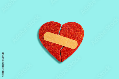 Broken habstract heart with medical patch on blue background photo