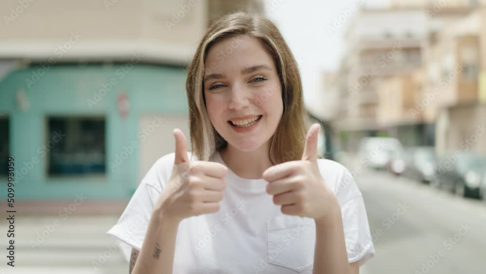 Young woman smiling confident doing ok sign with thumbs up at street Young woman smiling confident doing ok sign with thumbs up at street