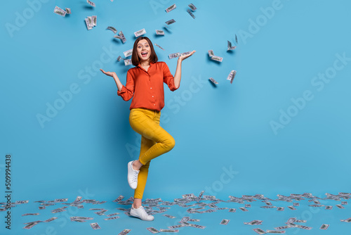 Full length body size view of attractive cheerful girl wasting cash having fun isolated over bright blue color background