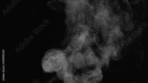 Water vapor. White jet of steam ascending and floats in air on black background. Micro drops of hot water are sprayed in air close up. Clouds of thick mist swirl. Smoke fog. Gaseous state. photo