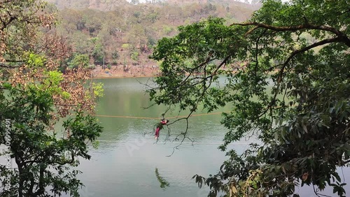 Man moving on zip line by lake photo