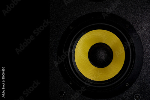 A high quality shot of a bookshelf speaker with yellow driver and jet black wooden cabinet.