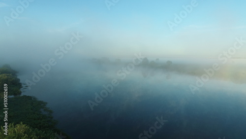 Bird's eye view of the mist over the river and meadows on an early summer morning
