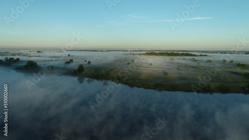 Bird s eye view of the mist over the river and meadows on an early summer morning