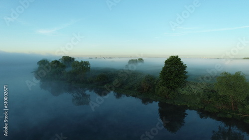 Bird's eye view of the mist over the river and meadows on an early summer morning